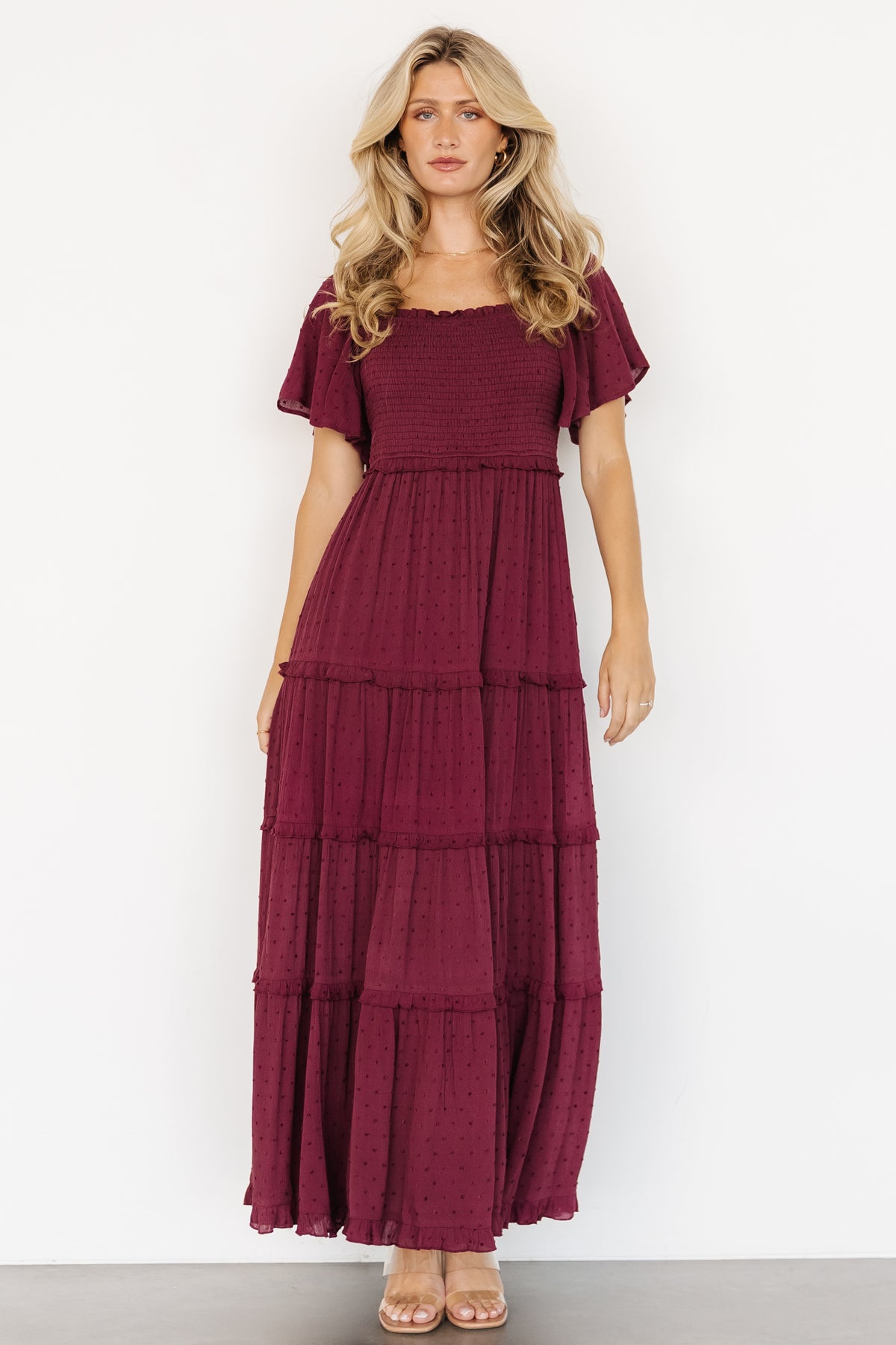 Styled look of the Lenora Smocked Dotted Maxi Dress in wine paired with neutral accessories for wedding guest styling ideas.