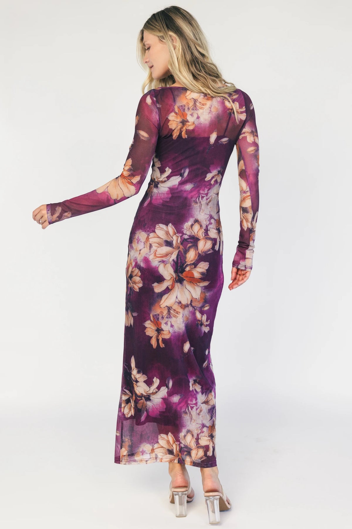 Model wearing a purple floral mesh midi dress with a round neckline, long sheer sleeves, and a fitted bodycon silhouette.