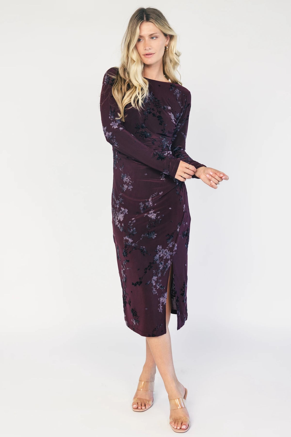 Model wearing a dark plum velvet floral midi dress with a boat neckline, long sleeves, and a fitted silhouette.