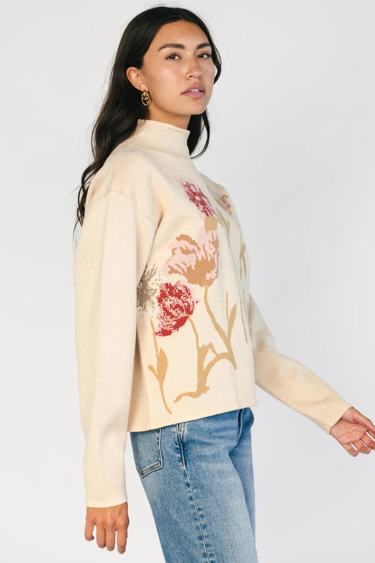 Natural knit sweater with a mock neckline, long sleeves, relaxed fit, and an embroidered floral motif at the neckline.