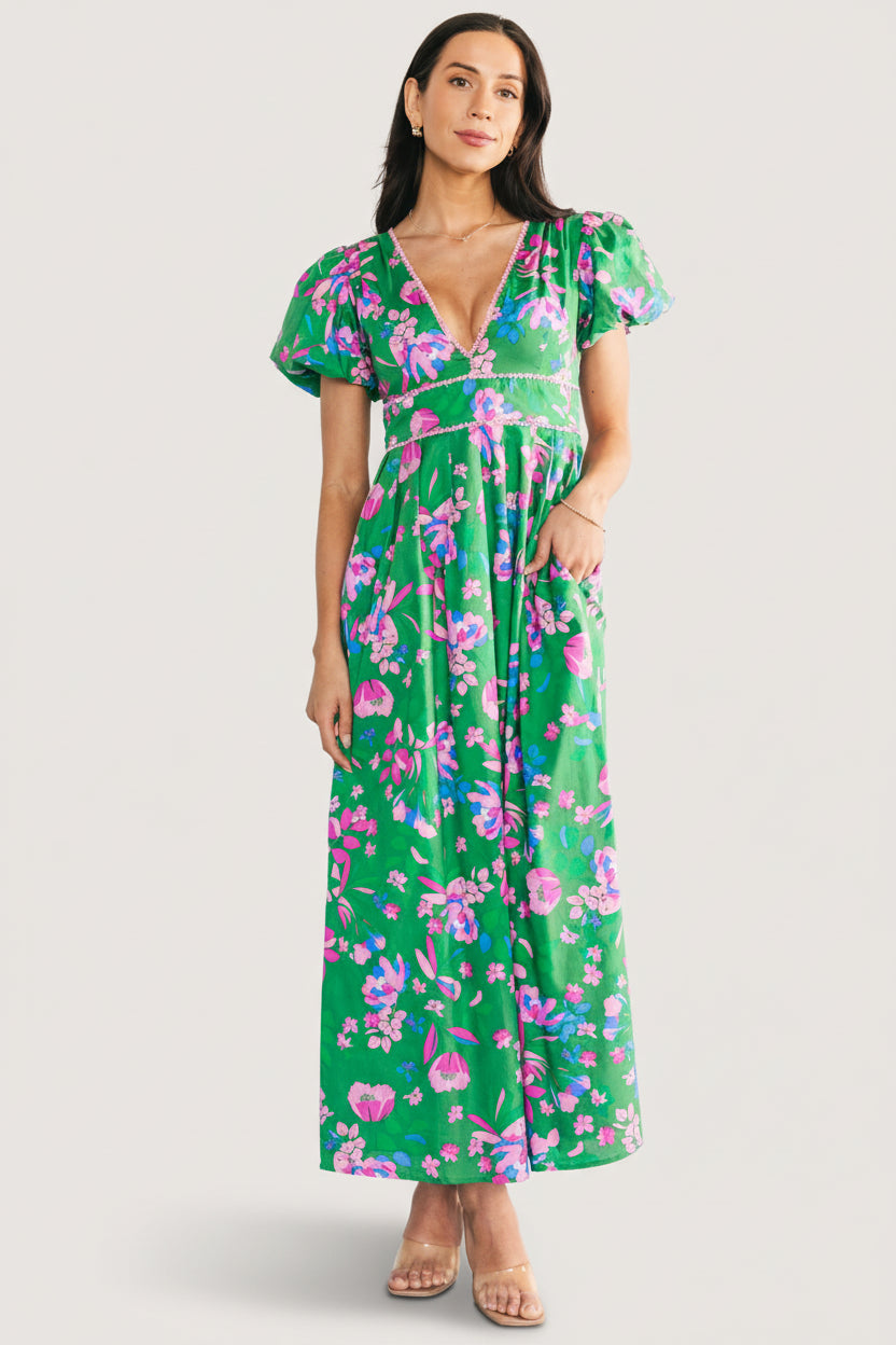 Side view demonstrating the hidden side pocket and the dress’s full lining and tailored maxi silhouette in green floral print.
