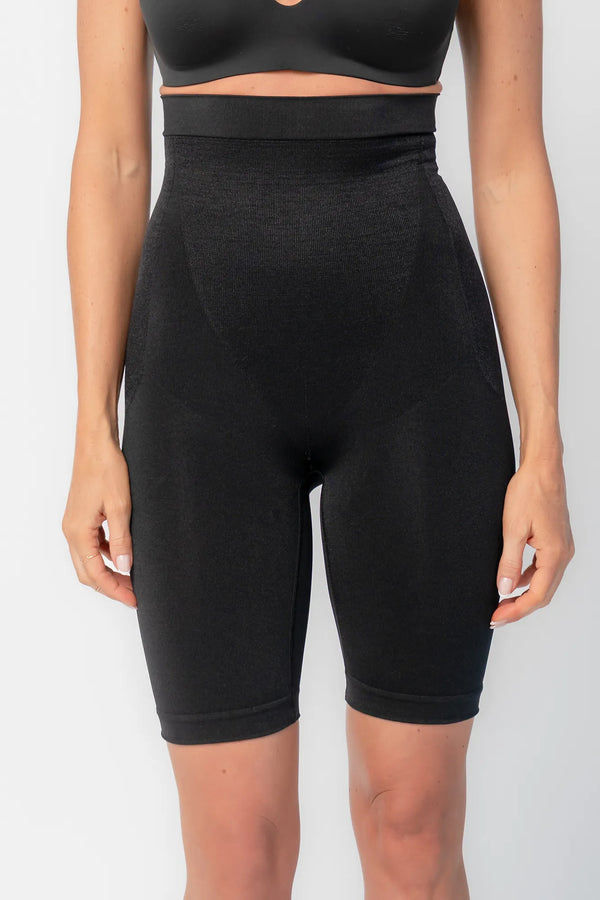 Model wearing black high-waisted shaping shorts with a seamless design and mid-thigh length.