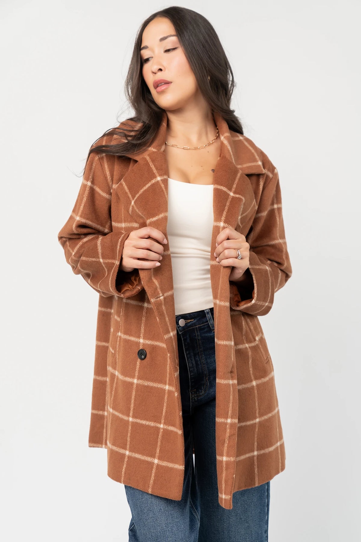Cognac plaid mid-length coat with a cream windowpane pattern, tailored collar, button-front closure, long sleeves, front pockets, and a fully lined interior.