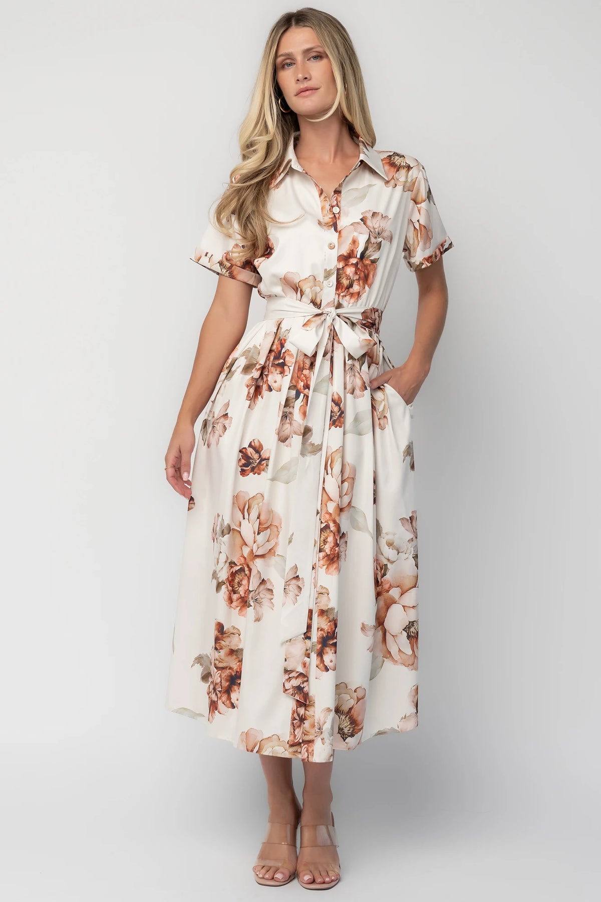 Model wearing the Blythe Midi Dress in Ivory Floral featuring a collared neckline, functional button-front bodice, short rolled sleeves, and a removable waist tie.
