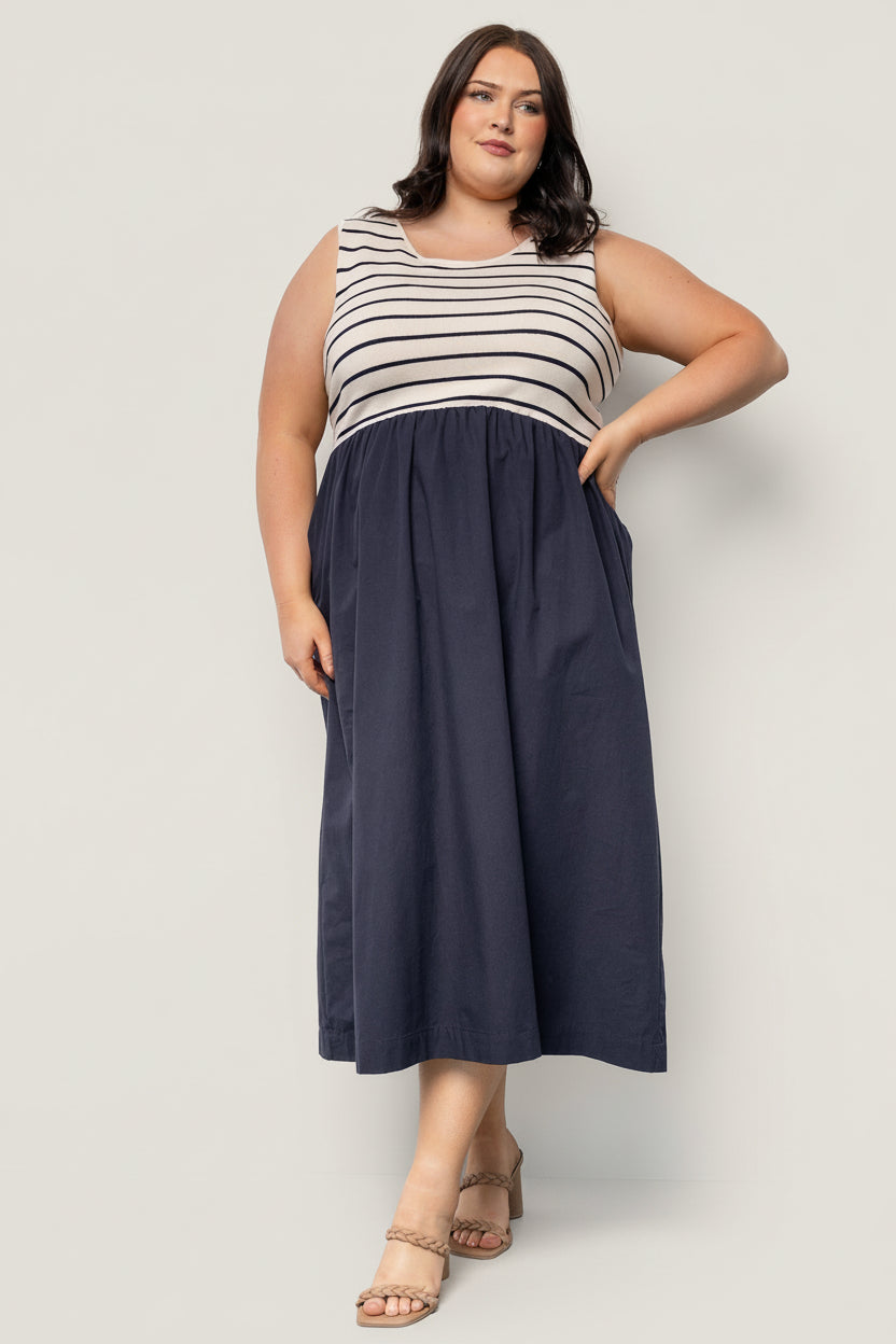 Styled look showing the navy stripe tank dress with a lightweight jacket, demonstrating versatility from daytime to evening occasions.