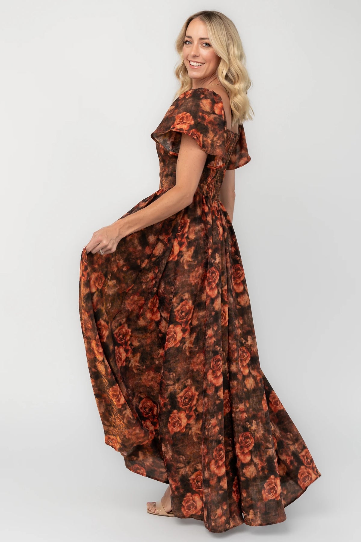 Dark rust floral shimmer maxi dress with a sweetheart neckline, flutter sleeves, empire waist, smocked back, and flowing full-length skirt.