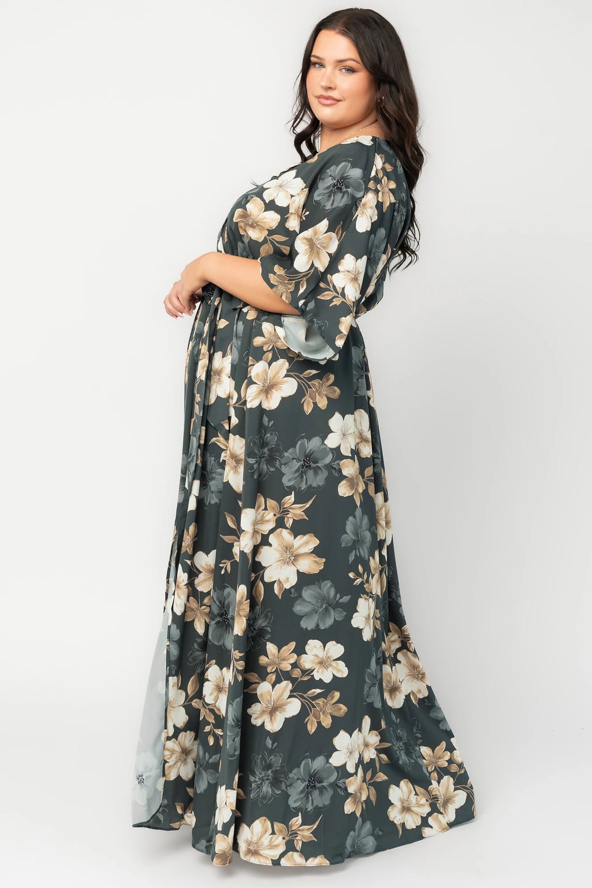 Model wearing a dark jade floral maxi dress with a surplice V-neckline, kimono sleeves, and an elastic waist with a removable sash tie.