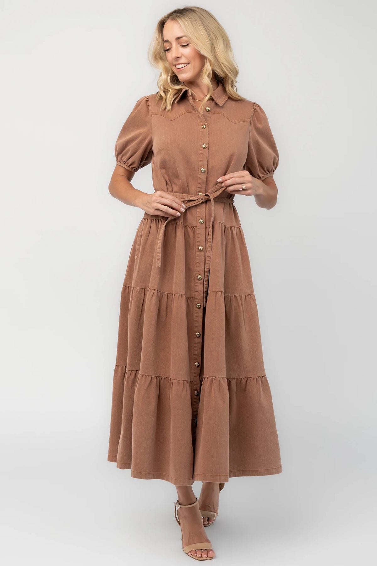 Dusty mocha midi dress with a collared neckline, gold-tone button-front closure, short puff sleeves, removable waist tie, and tiered skirt.