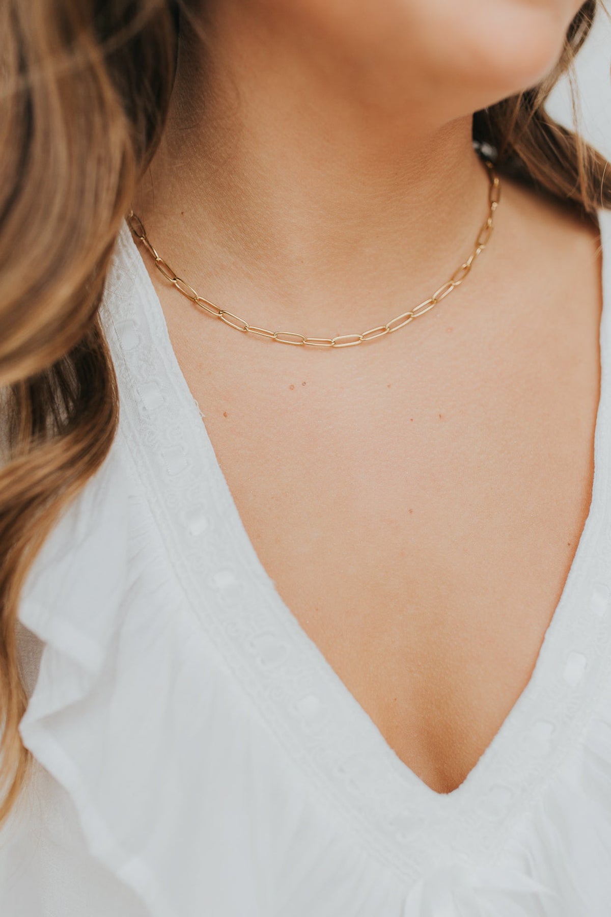 Lifestyle image of The Eloise Necklace worn close to the neckline, demonstrating how the elongated links create an elegant, modern silhouette.