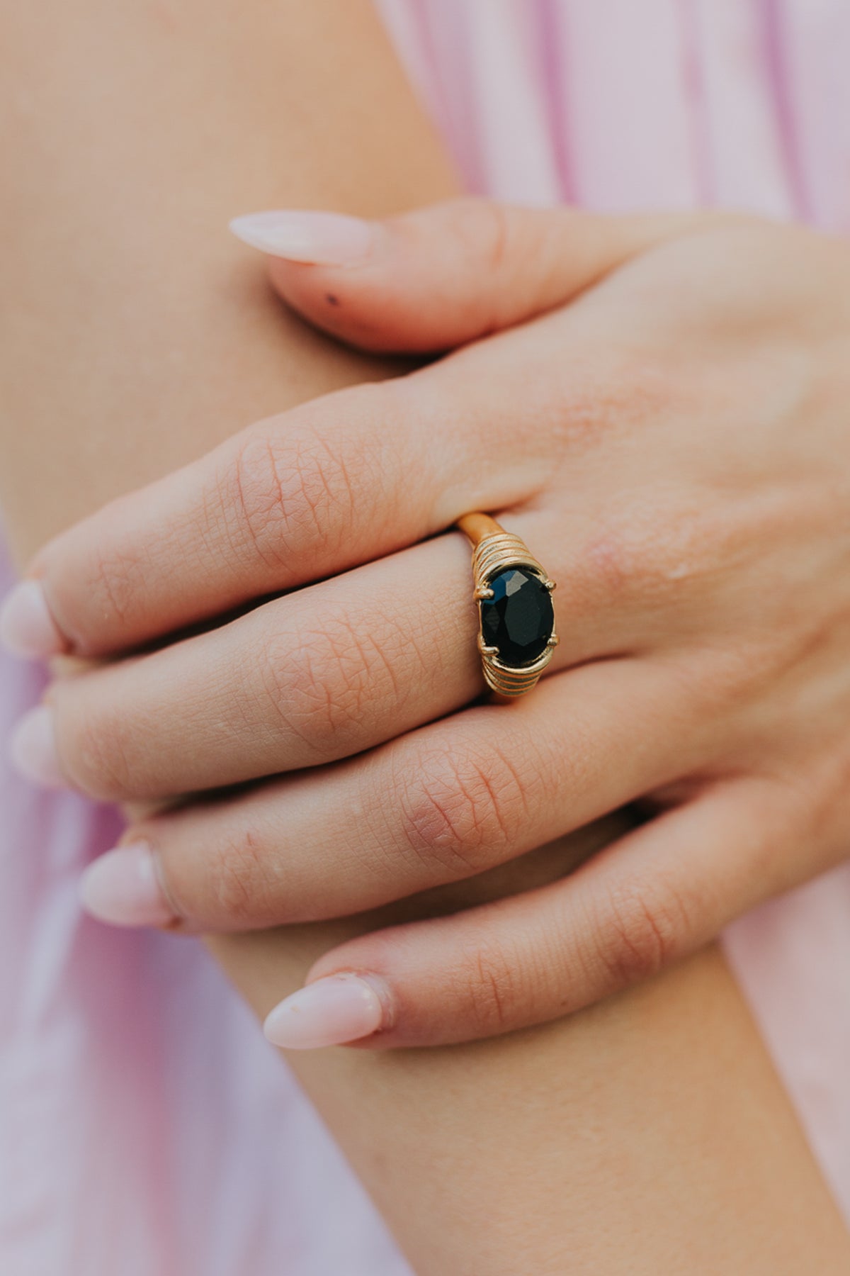 Styled lifestyle image of Maddie ring paired with bracelet, showcasing black onyx contrast against warm gold-toned metal and everyday styling.