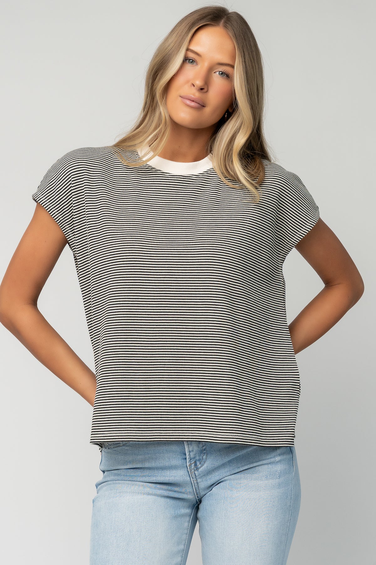 Back view of Millie Striped Top in black and off-white showing overall stripe pattern, seam detail, and slightly asymmetrical hem.