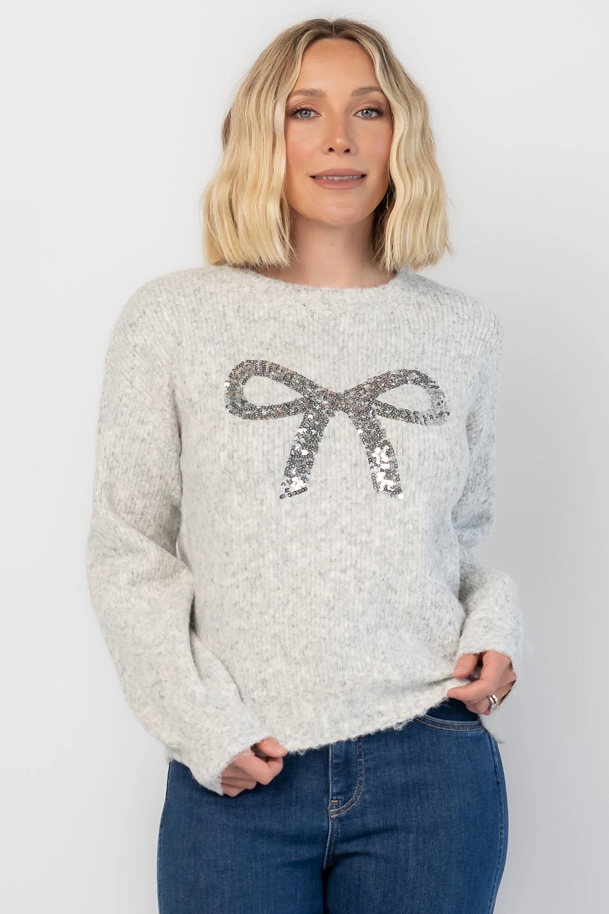 Bow Sweater in Gray with a sparkling sequin bow at the front, a crew neckline, and a heathered knit finish.
