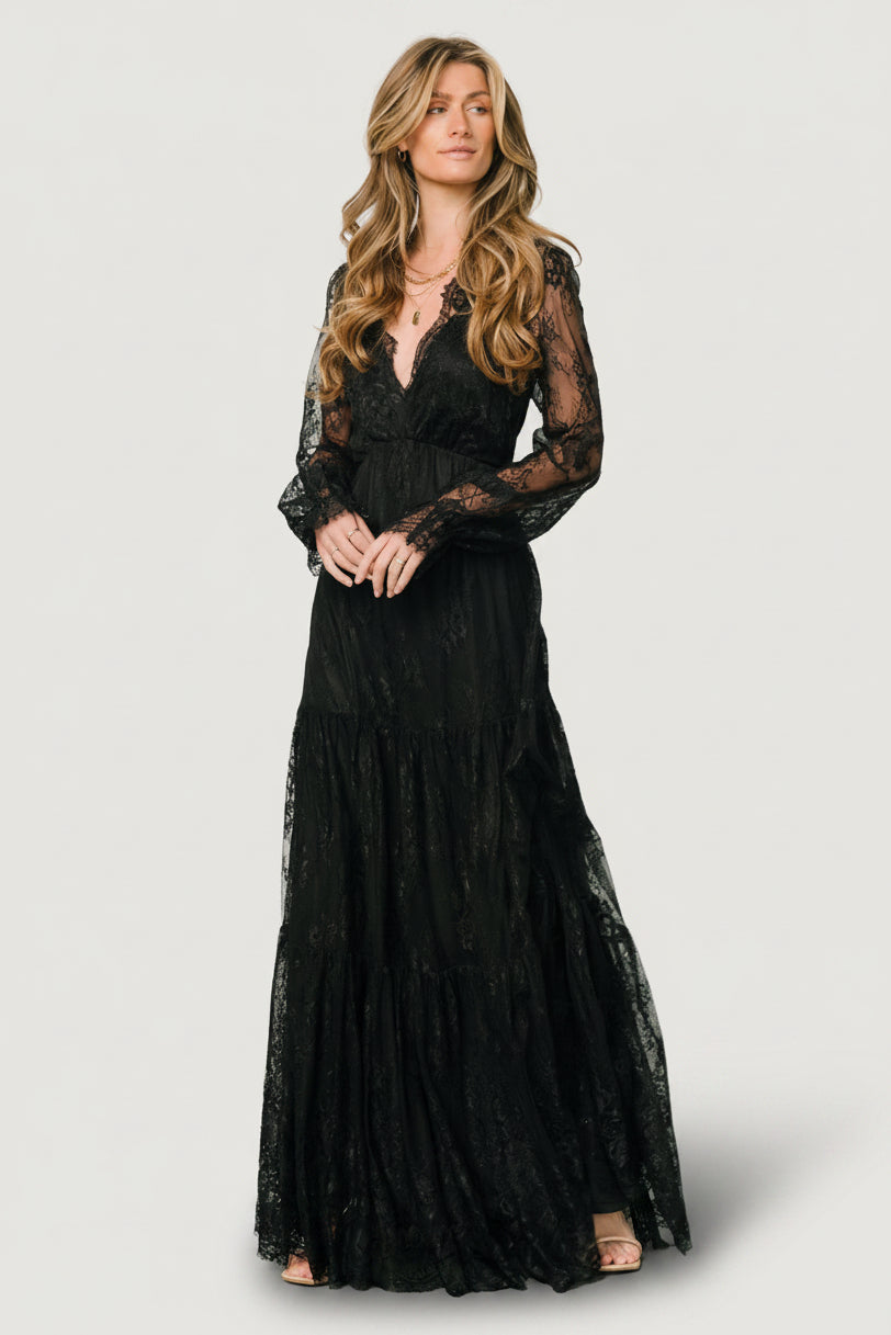 Gloria Lace Maxi Dress in Black with deep V-neck, sheer long sleeves, elastic waist, and three-tiered lace skirt.