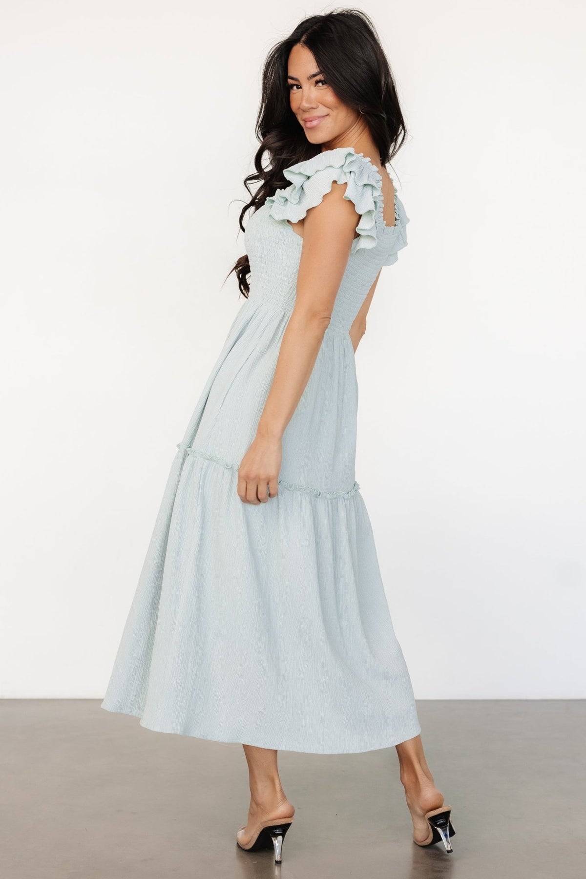 Styled full-length image of the light blue smocked midi dress on model, showing length, fit, and how the skirt falls for everyday and event wear.