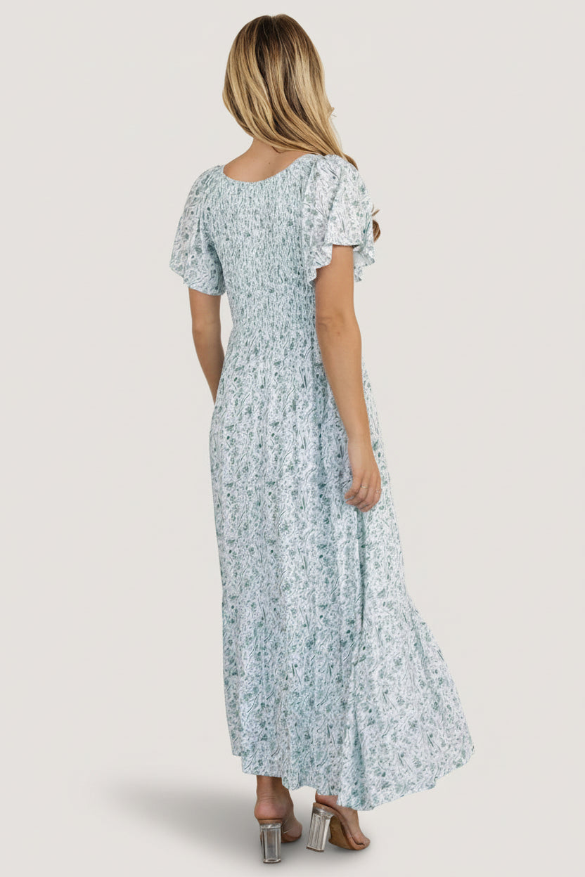 Back view of Joanie smocked midi dress showing gathered smocking at the bust, unlined flutter sleeves, and flowing skirt length.