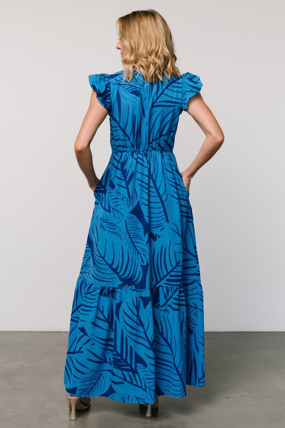 Studio shot of Kaia Button Maxi Dress in blue botanical print on model, emphasizing airy movement, resort-ready silhouette, and practical pockets.