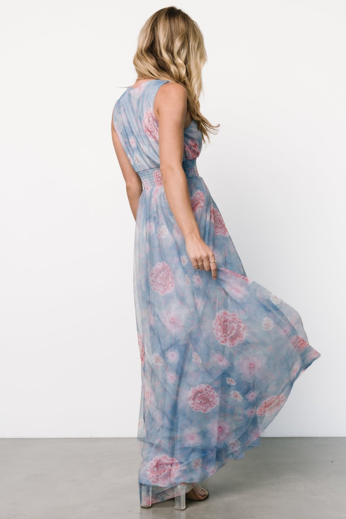 Model wearing light blue tulle maxi dress with pink florals, styled with minimal jewelry to showcase neckline and waist.