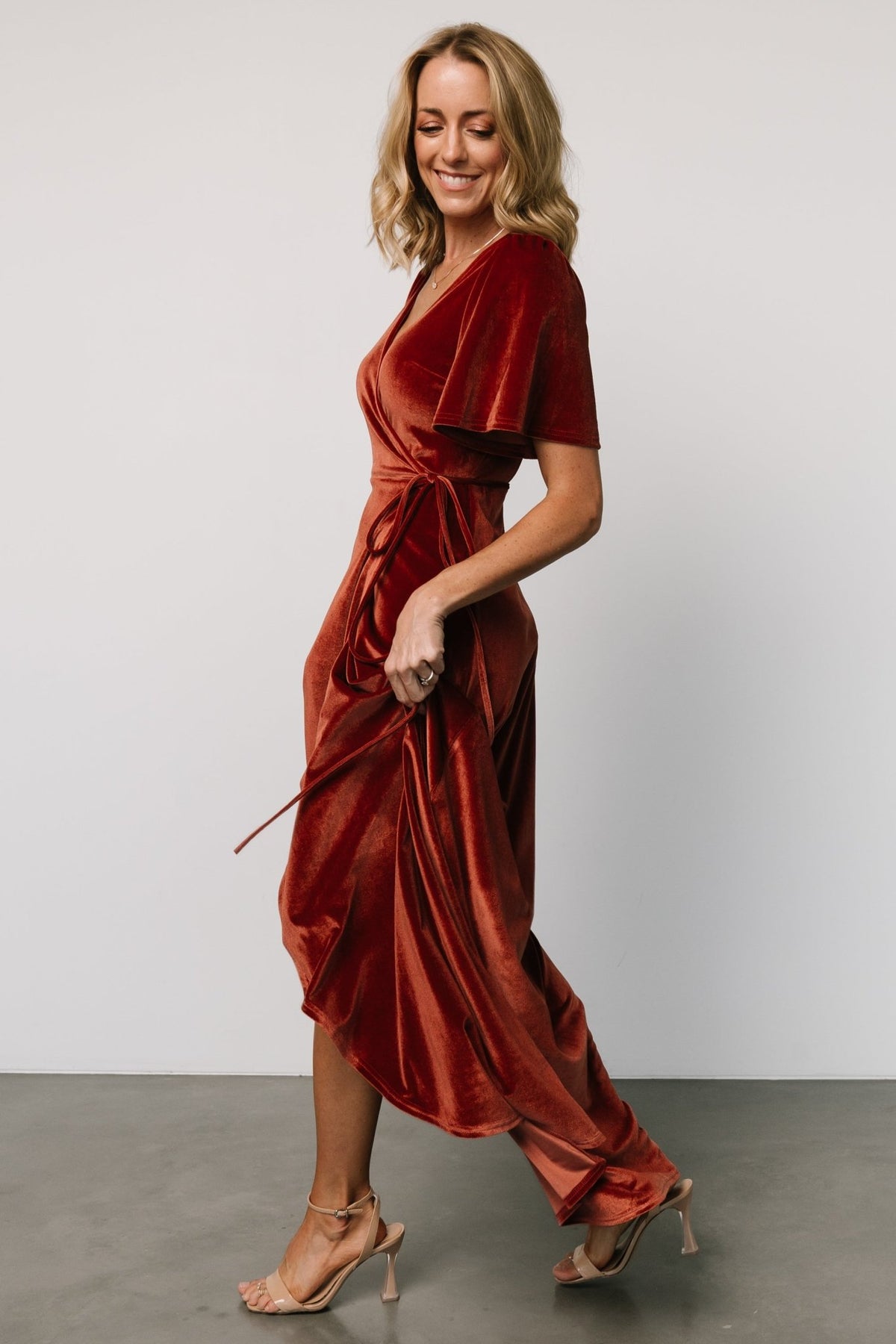 Rear and three-quarter view of the Cinnamon Katelyn velvet maxi wrap dress showing back coverage, skirt flow and how the wrap ties sit at the waist.