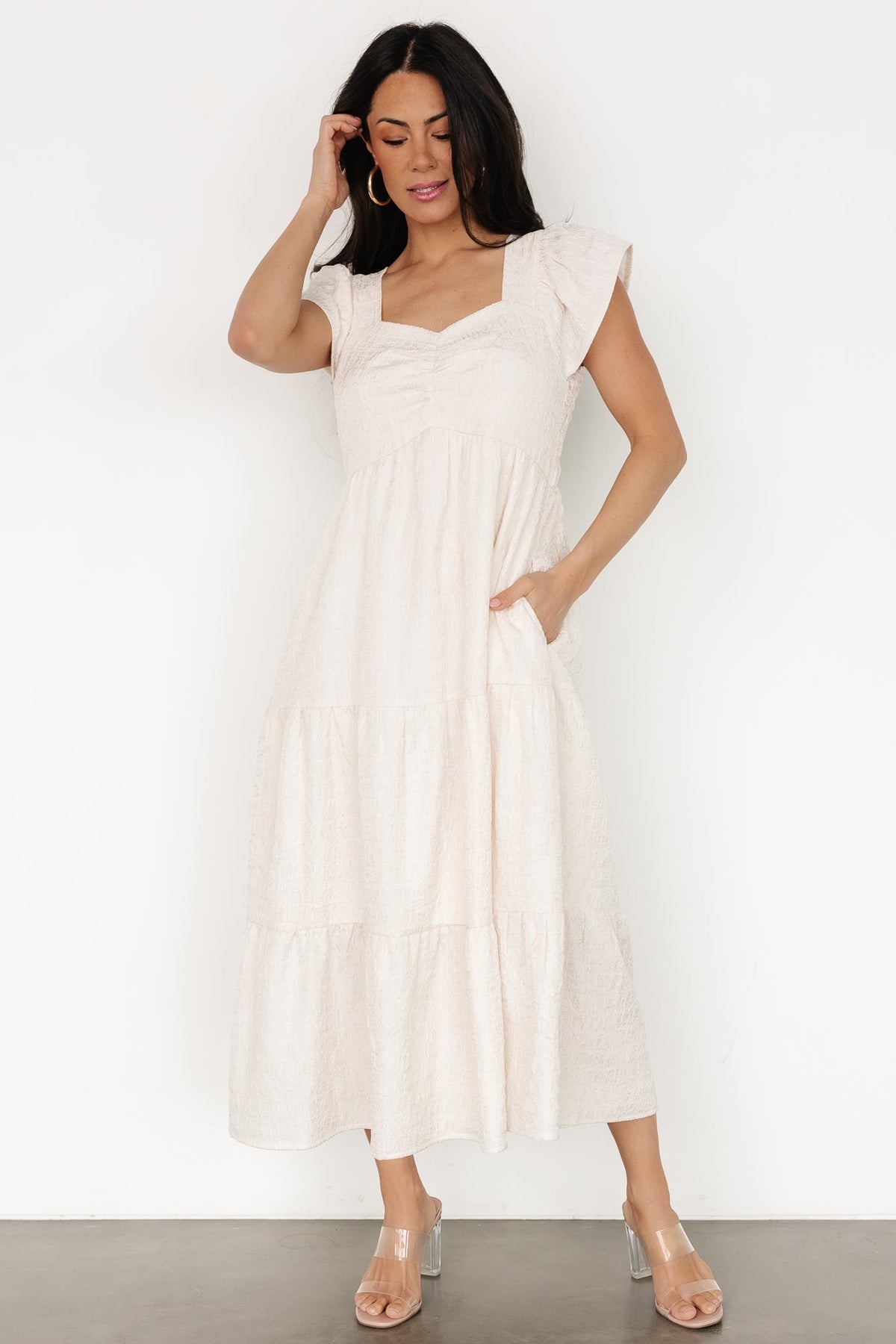 Styled ensemble showing the Kesler Midi Dress in cream paired with simple accessories, showcasing its occasion versatility.