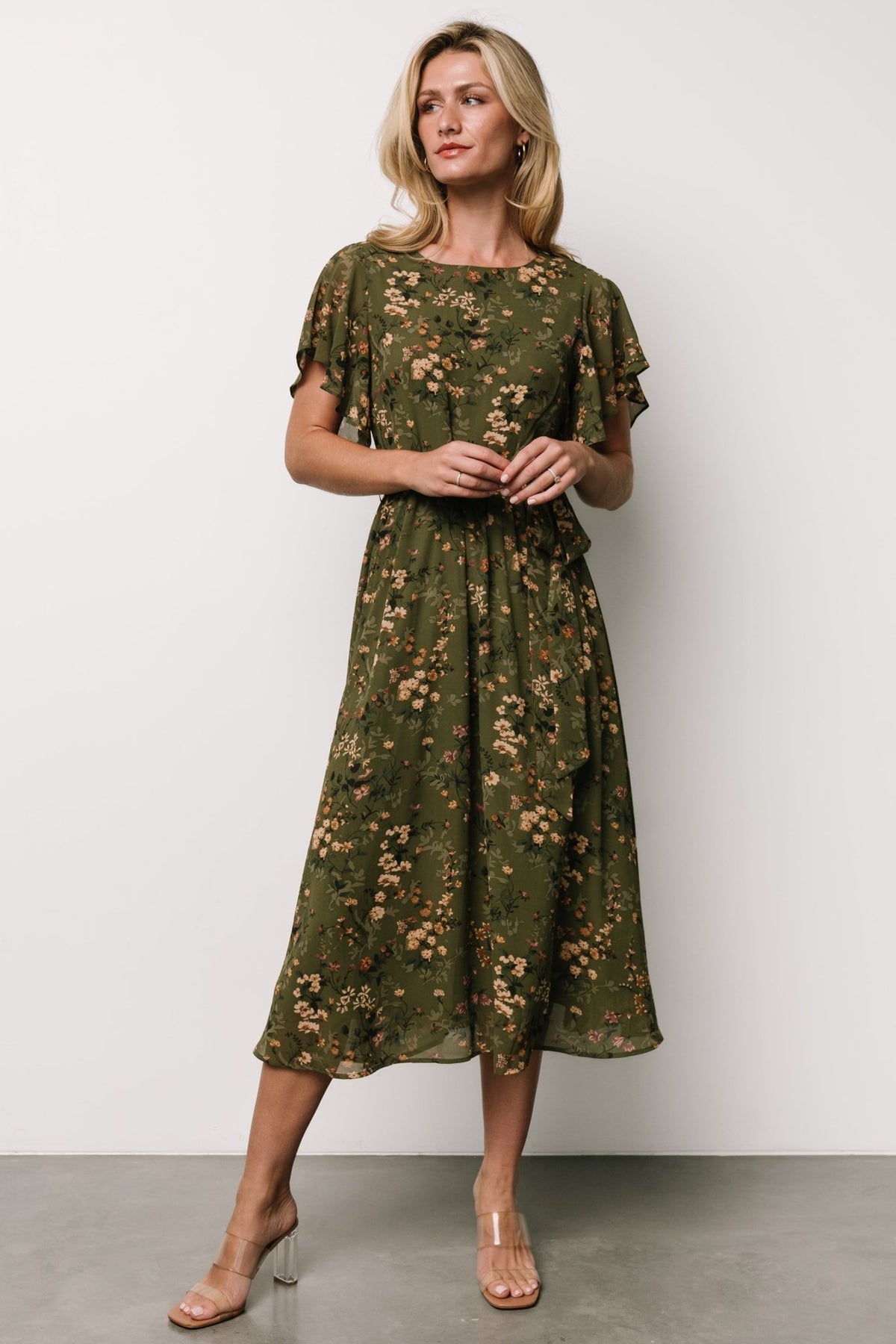 Styled flat-lay of the olive floral midi dress with detached self-tie sash, highlighting round neckline, ruffle hem and lightweight construction.