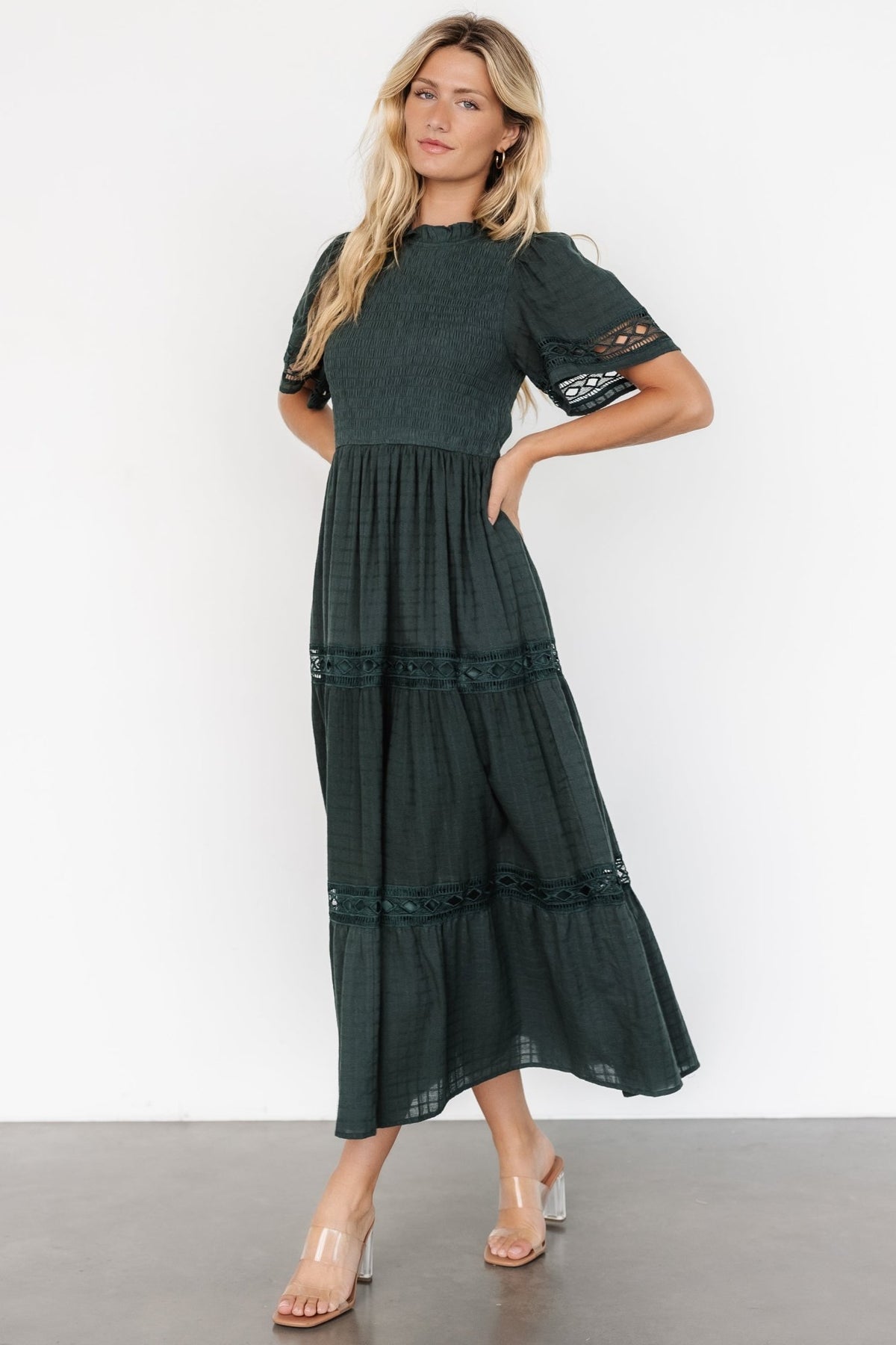 Styled flat-lay of the Loveland Geo Lace Maxi Dress in dark green, showing tiered skirt construction, lace details, and fabric composition.