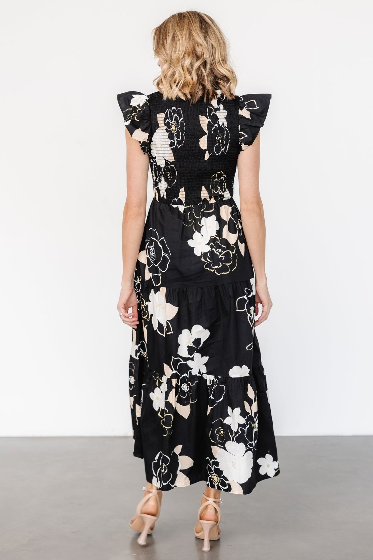 Model wearing Ranchero smocked maxi dress in black floral print, size reference and styling suggestion with sandals to show fit and length.
