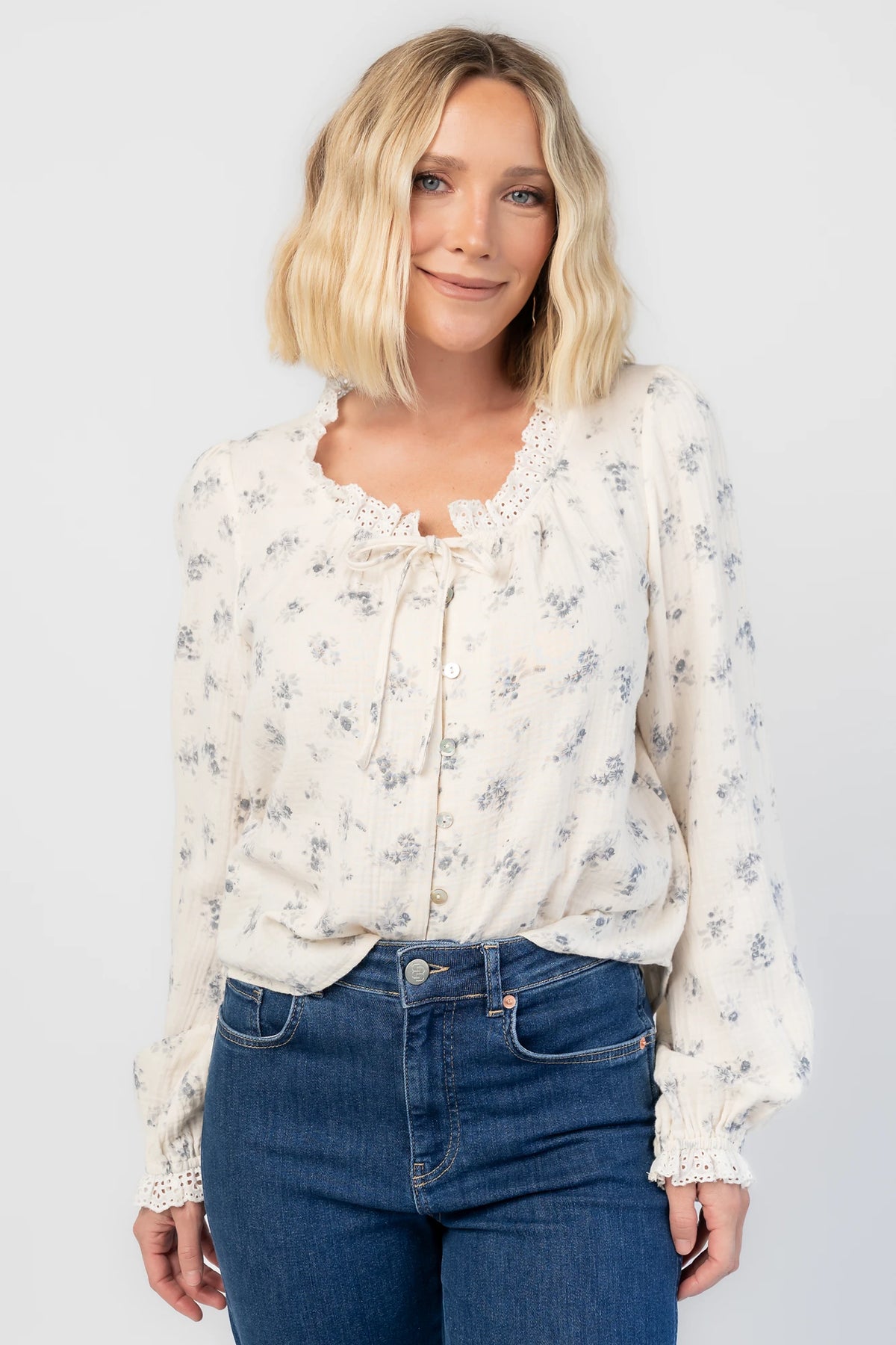 Stephanie Button Front Blouse in Ivory + Blue Floral with a lace-trimmed tie neckline and a button-front design.