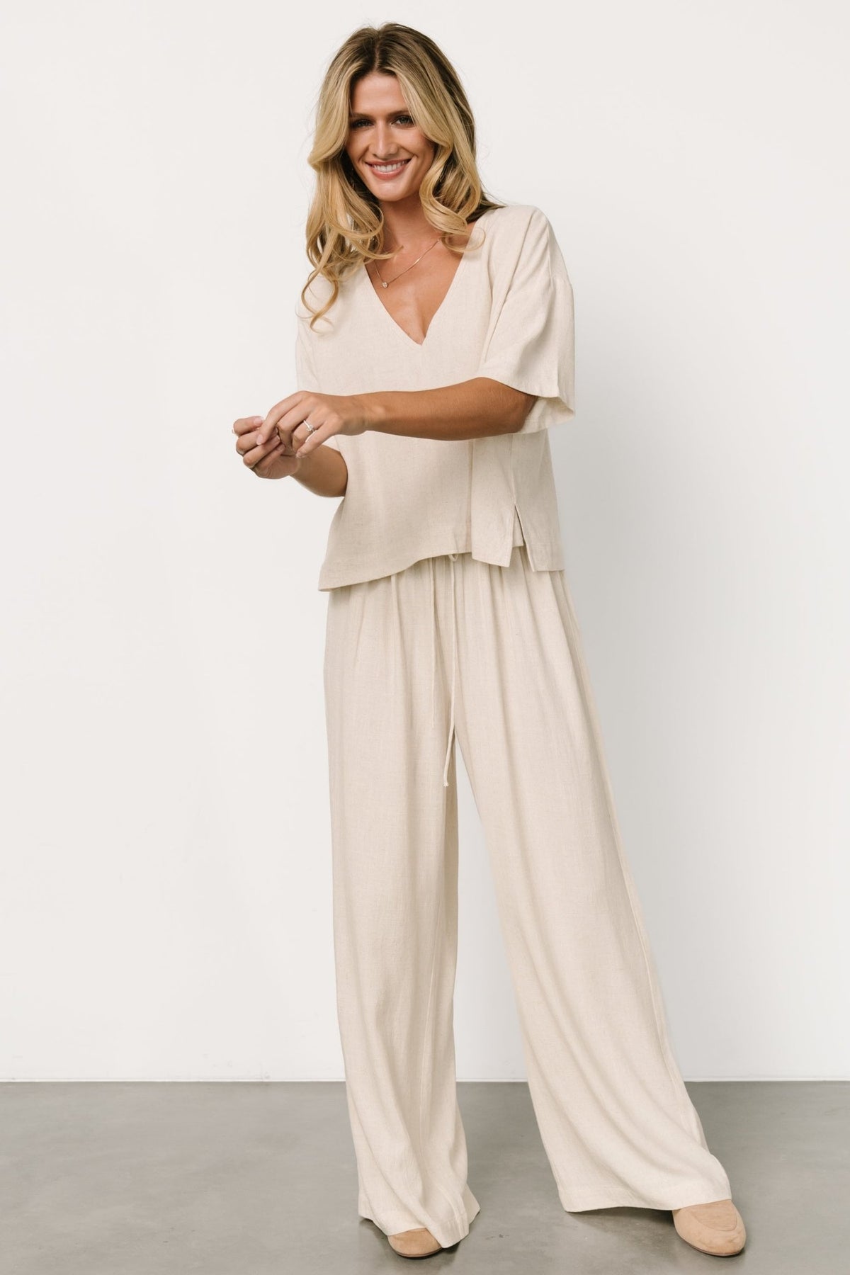 Styled outfit shot: natural linen-blend two-piece paired with sandals, illustrating versatile travel-to-evening styling options.
