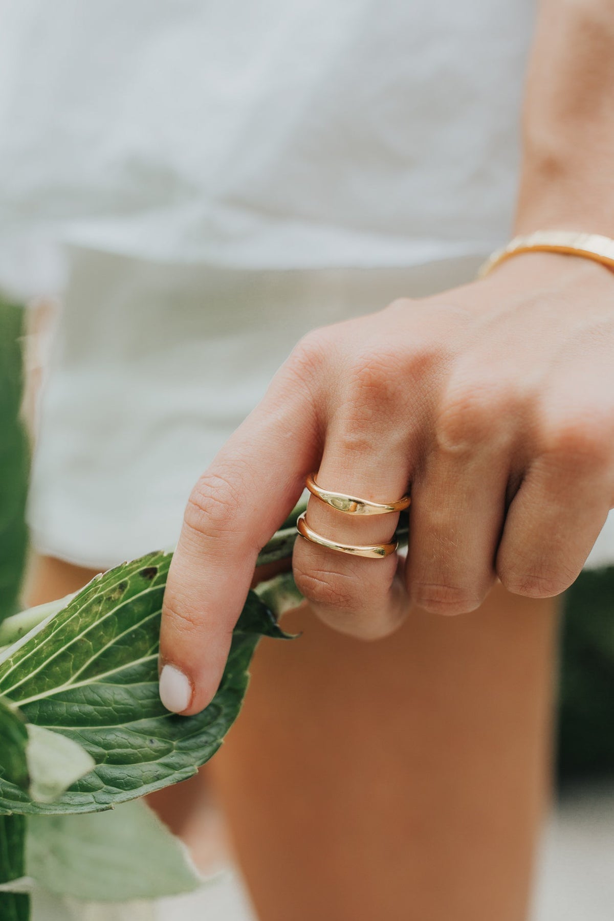 Flat lay of the Florence ring with complementary bracelets and necklaces, demonstrating styling options and polished gold finish.