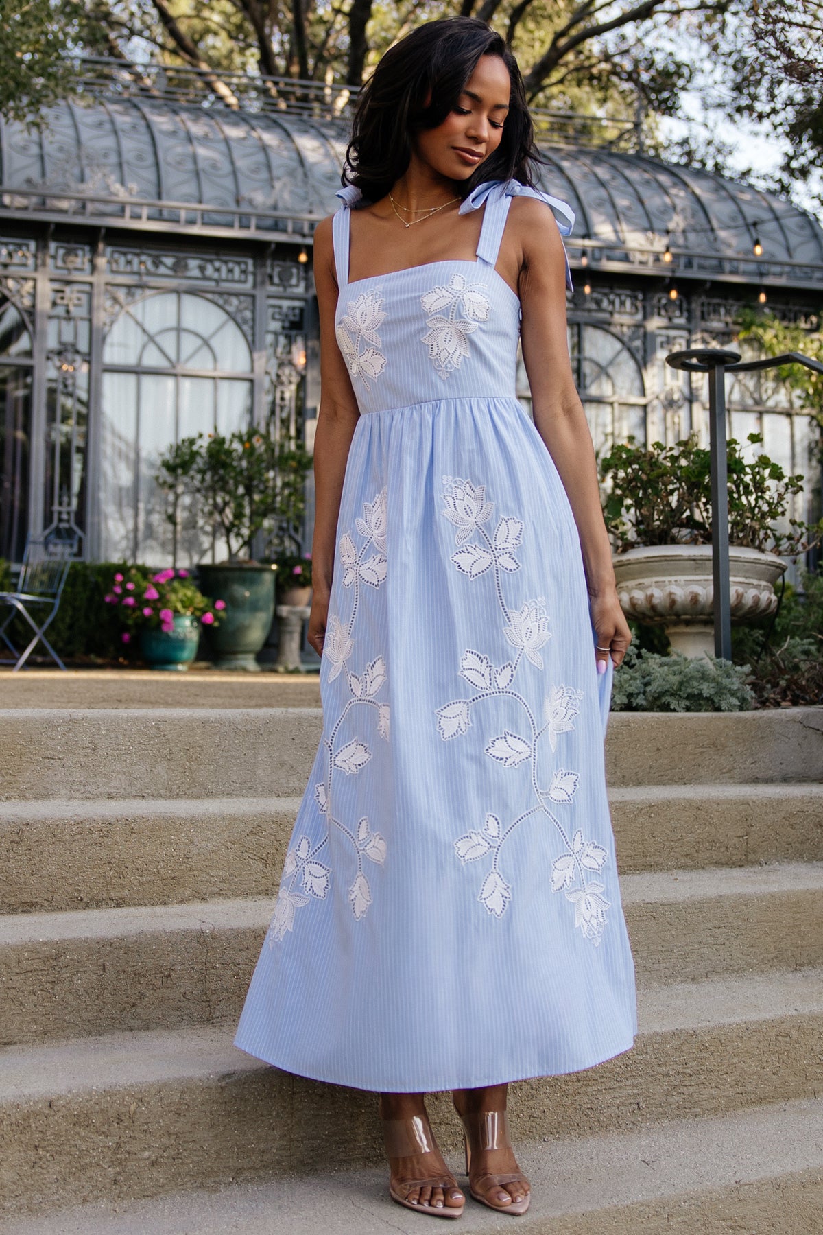 Front view of Enora embroidered maxi dress in blue and white stripes with floral embroidery, square neckline and self-tie straps.