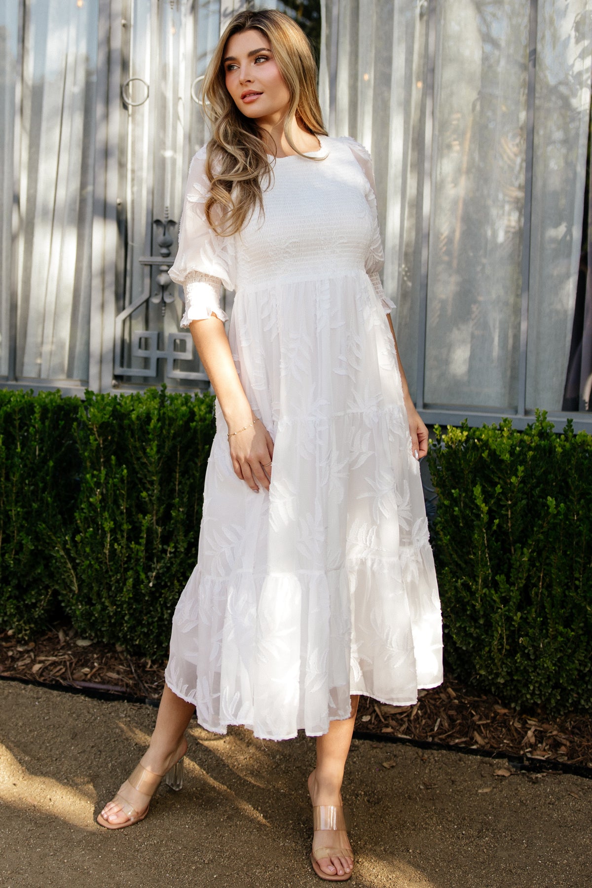 Flat-lay of off-white Nellie Smocked Midi Dress highlighting round neckline, puffed sleeves, smocked bodice and tiered skirt silhouette.