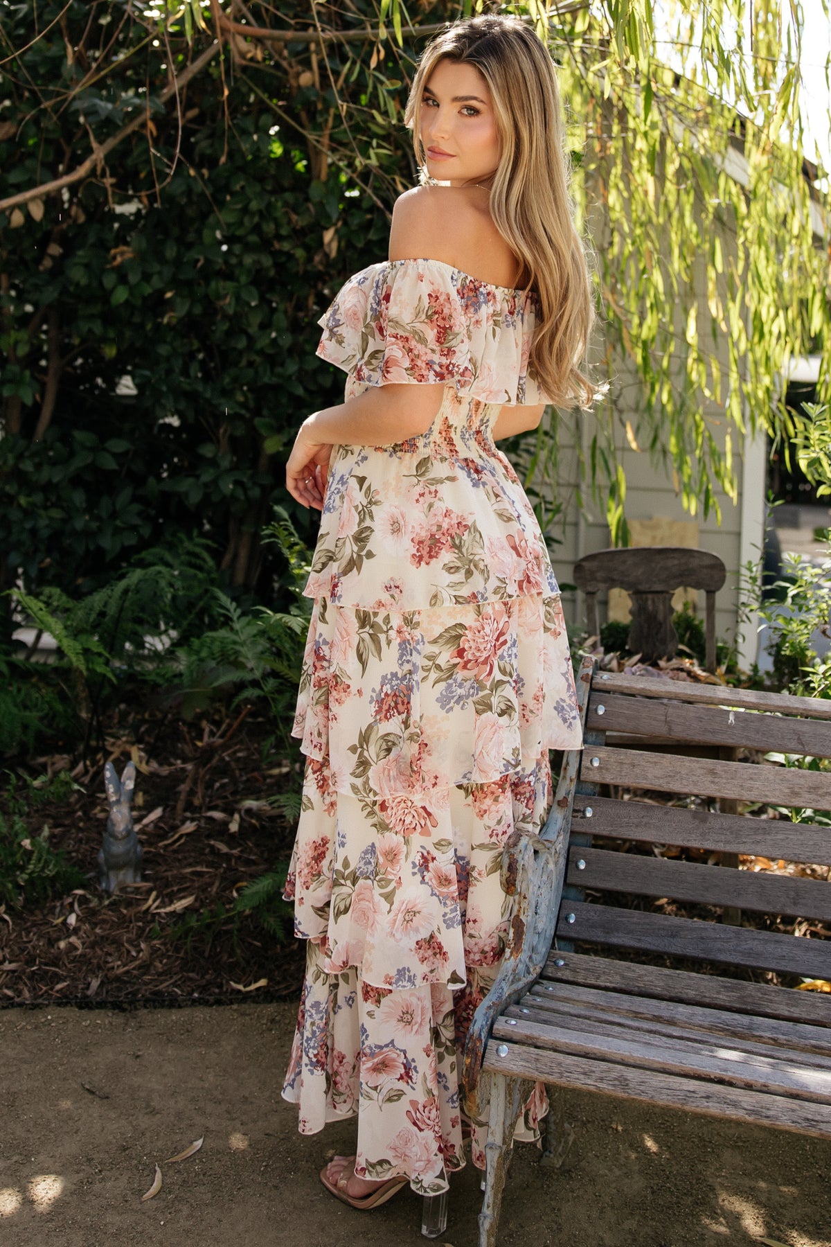 Full-length image of the multi floral maxi dress tucked at the smocked waist, showcasing four-tiered skirt and graceful hem movement.
