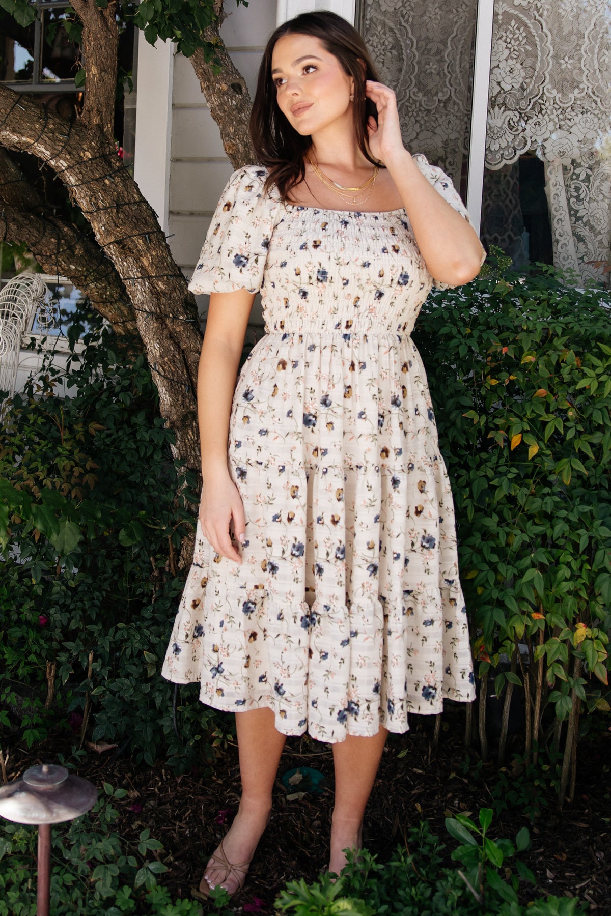 Close-up of the smocked bodice and square neckline on the beige floral Mattea dress, showing texture and stitch detail on fabric.