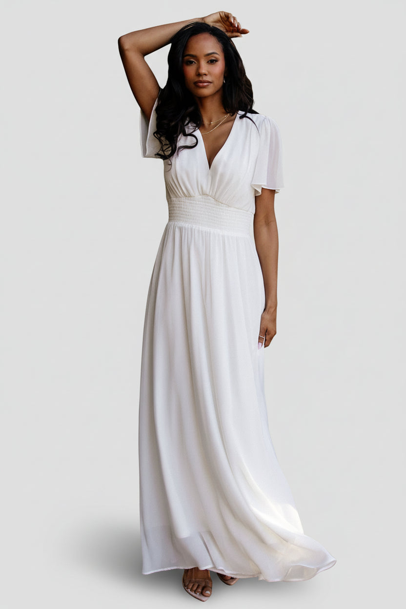 Front view of Birdie Chiffon Maxi Dress in white on model, showing V-neck, flutter sleeves, smocked waist and flowing skirt, full-length.