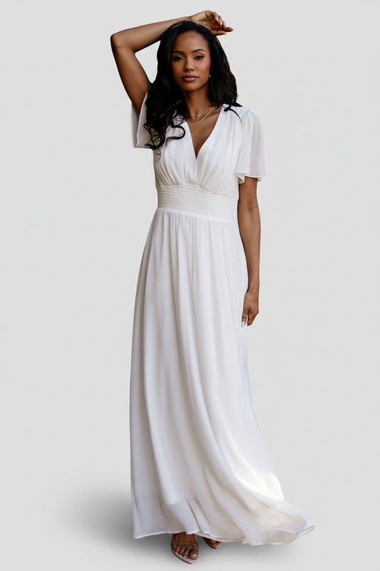 Front view of Birdie Chiffon Maxi Dress in white on model, showing V-neck, flutter sleeves, smocked waist and flowing skirt, full-length.