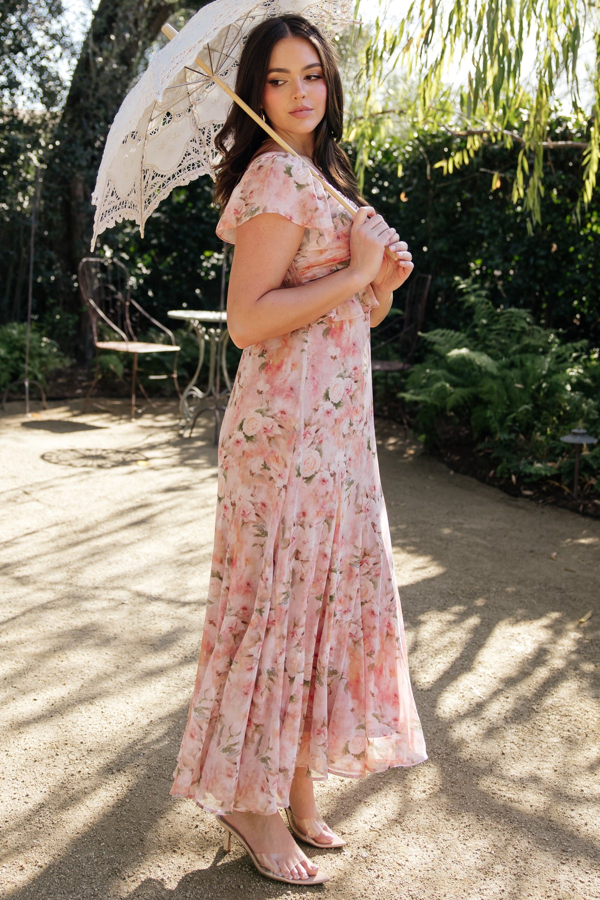 On-model shot of Teuila Midi Dress highlighting inverted ruffle V-waist, flutter sleeves, and flowy godet-style skirt in blush floral print.