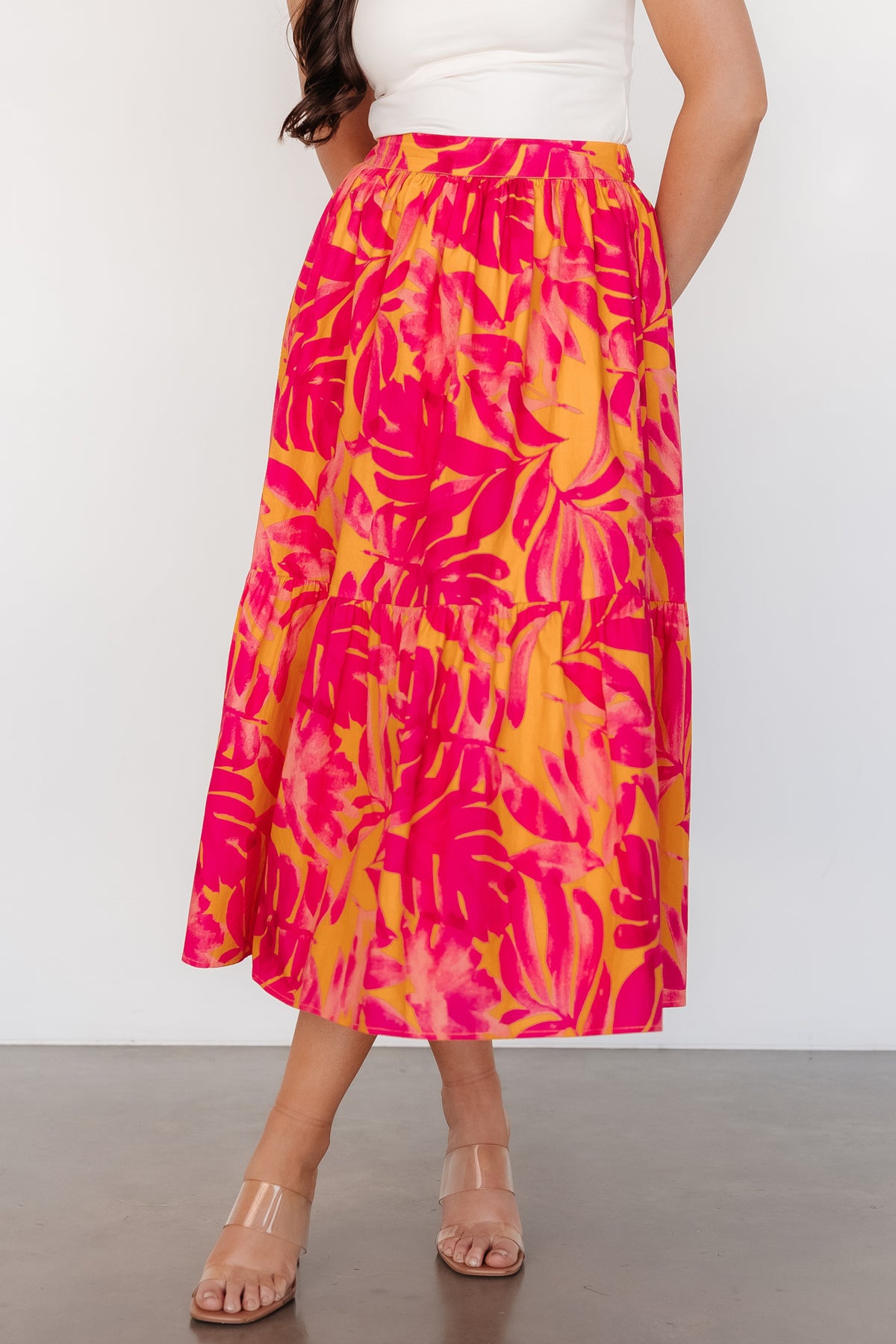 Front view of Luana tiered midi skirt in orange and fuchsia leaf print, showing flowing tiers and full lining for coverage.