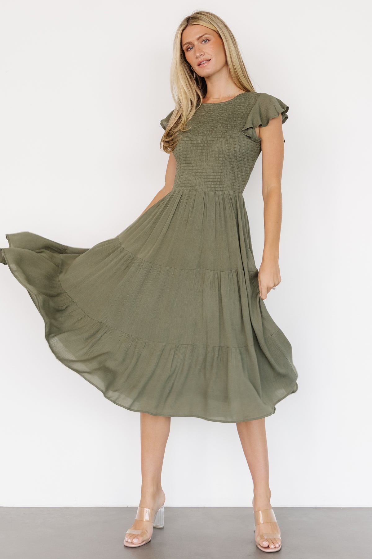 Detail view of skirt tiers and hem of Loretta Smocked Midi Dress in dark sage, demonstrating movement and full lining.