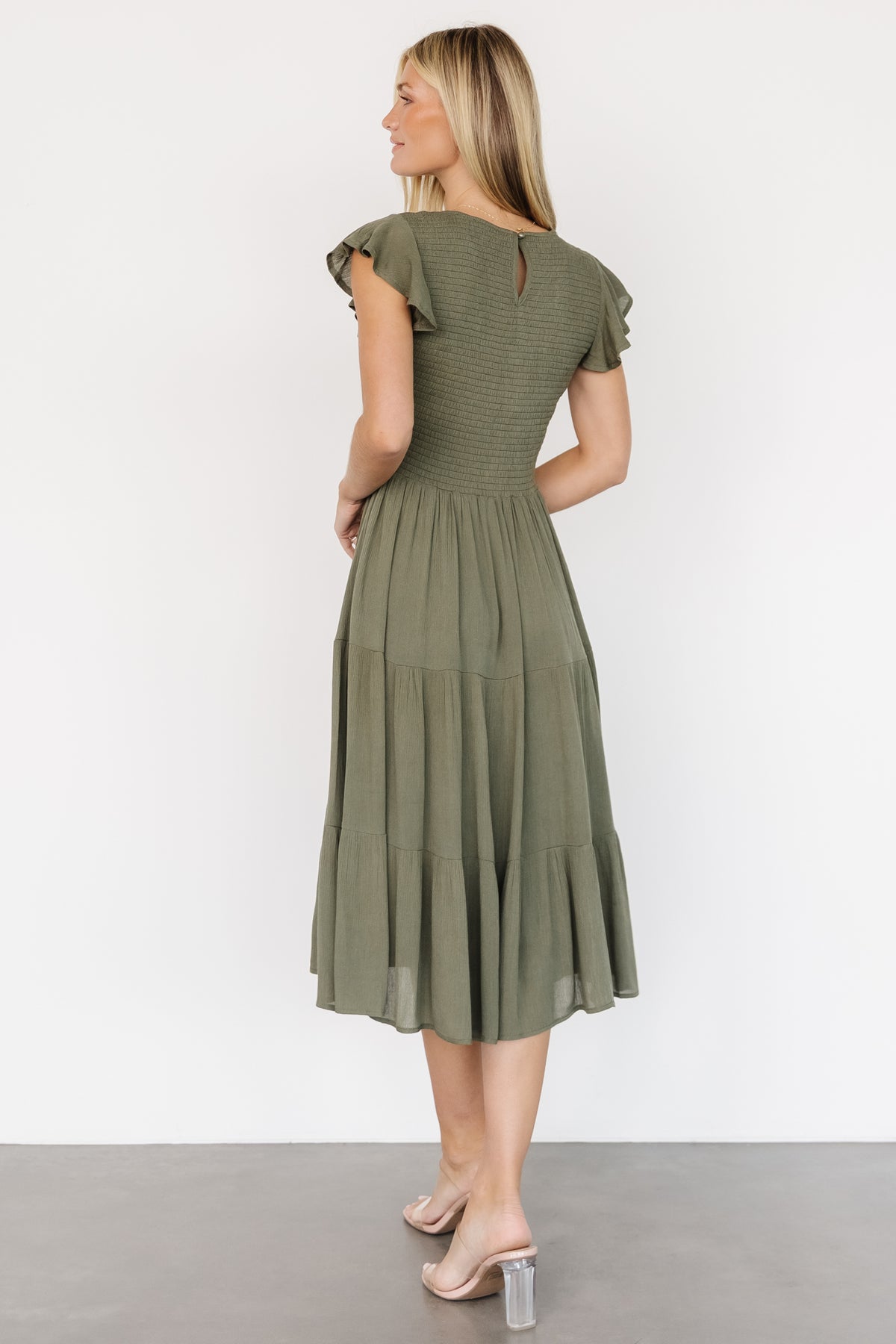 Full-length shot of Loretta Smocked Midi Dress in dark sage showing silhouette, three-tier skirt, and how the skirt falls above the ankle.