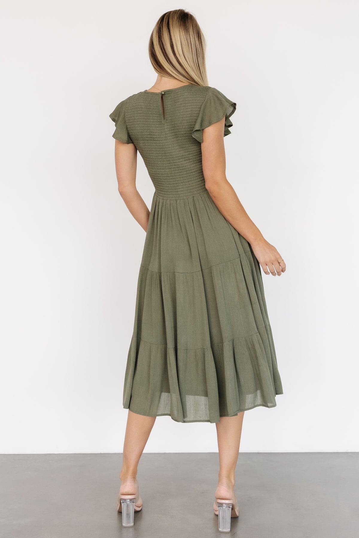 Back view of Loretta Smocked Midi Dress in dark sage showing keyhole closure, smocked back detail, and flutter sleeves.