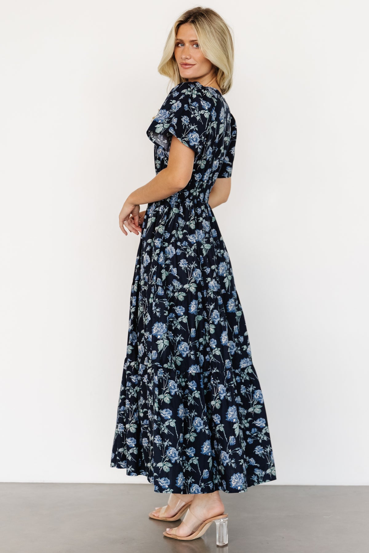 Styled outfit image with Kristin Maxi Dress, showcasing navy floral print, smocked waist, short sleeves and options for casual accessorizing.