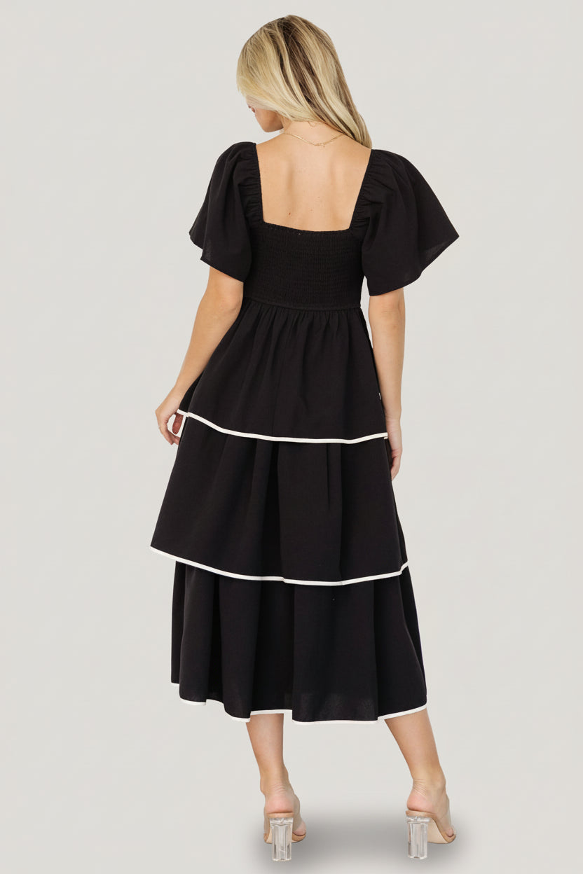 Full-length image of the Madrid Tiered Midi Dress in black, showing natural waistline and overlapping tiers for movement and silhouette.