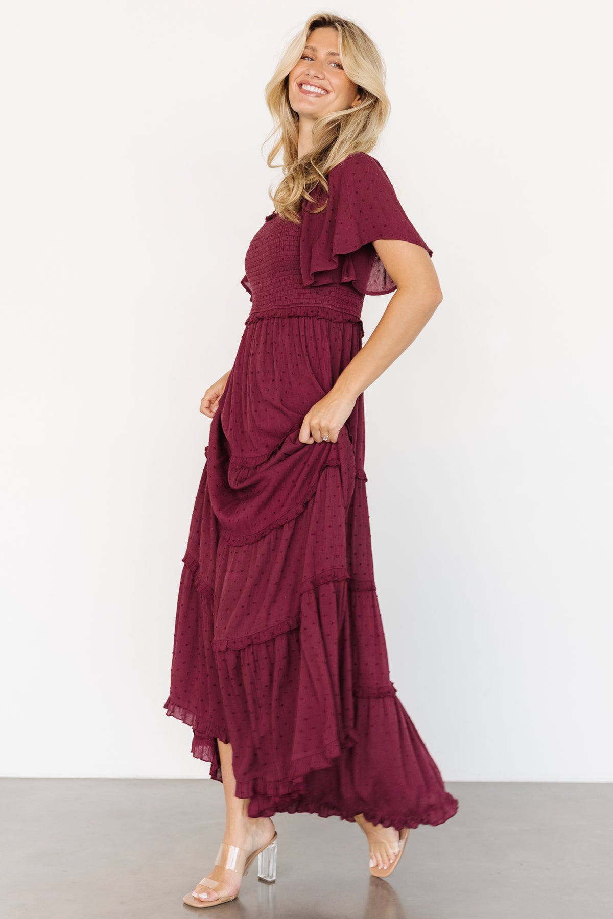 Back view of the Lenora Smocked Dotted Maxi Dress in wine, showing full maxi length and ruffle tiering at the hem.