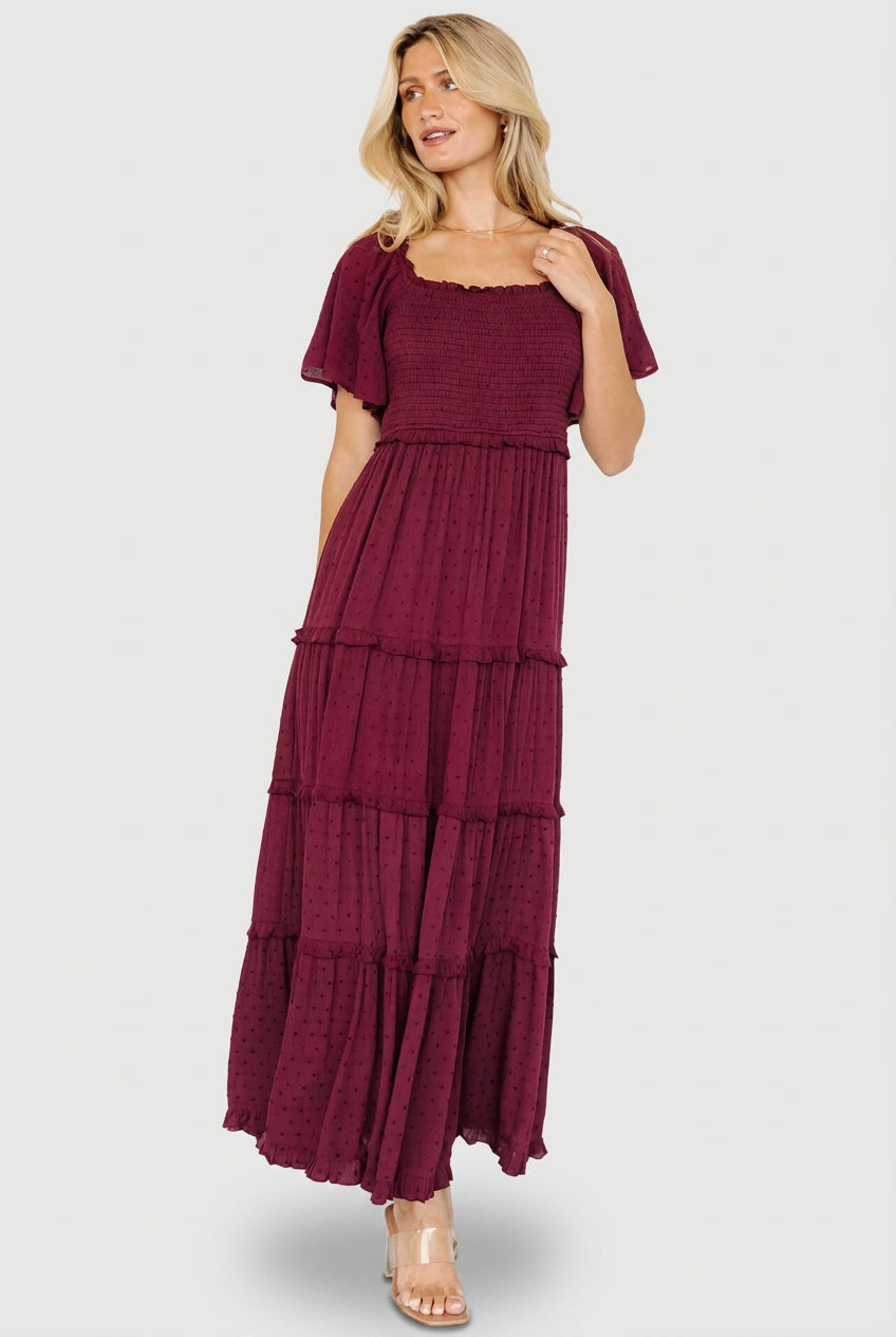 Front view of model wearing Lenora Smocked Dotted Maxi Dress in wine, showing square neckline, smocked bodice, and flutter sleeves.
