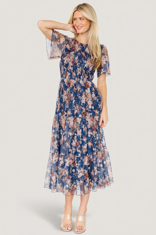 Front view of dark blue embroidered tulle midi dress with blush and berry floral embroidery and subtle gold-thread accents across the overlay.