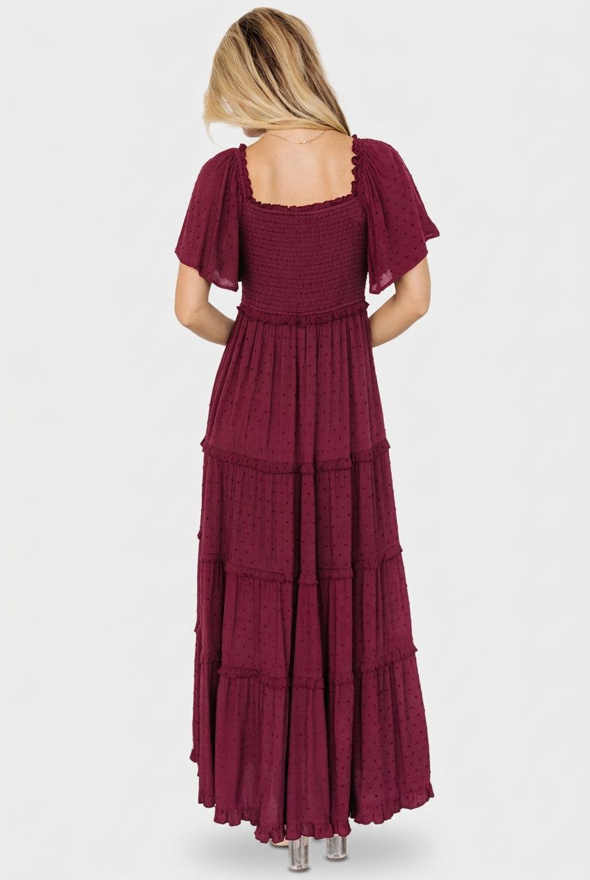 Close-up detail of the Lenora dress smocked bodice and dotted fabric texture in wine color, showing elastic shoulders.