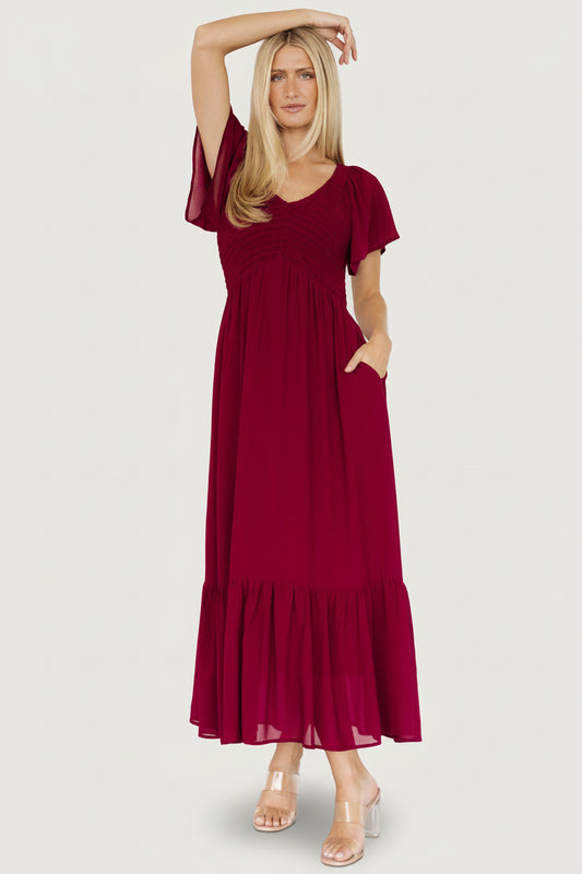 Front view of Monica Smocked Maxi Dress in mulberry showing V-neck, smocked bodice, flutter sleeves, and flowing tiered skirt.