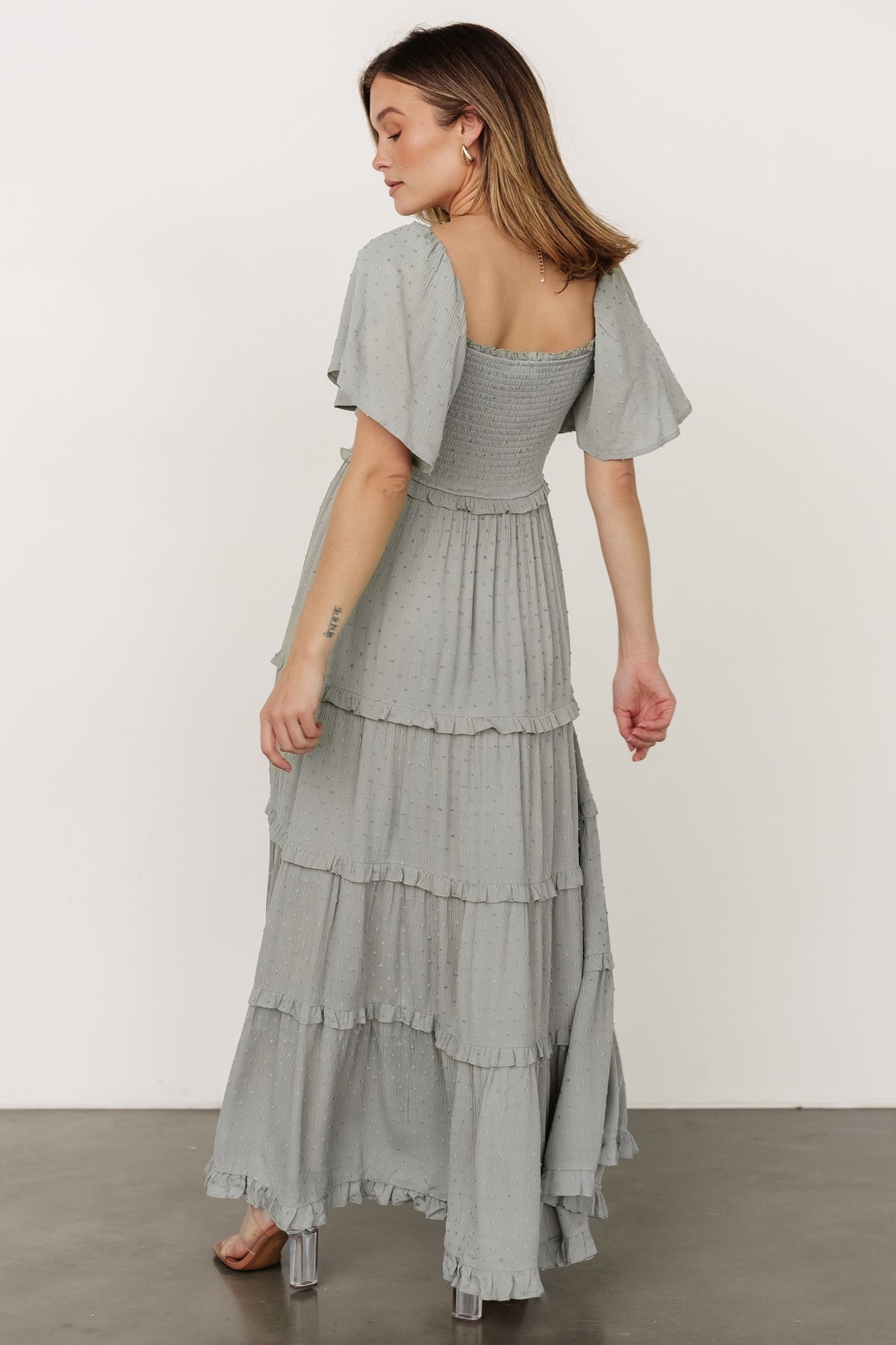 Back and side view of Lenora smocked dotted maxi dress in sage, showing ruffle-tiered skirt, elastic waist detail, and natural drape.