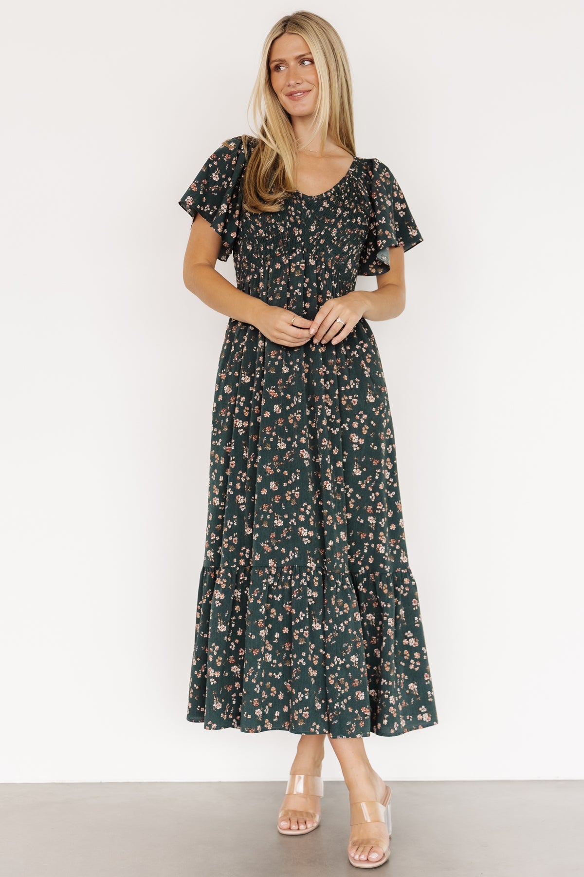 Three-quarter view of the dress highlighting the empire waist, hidden side pocket, and textured chiffon floral print in deep jade tones.