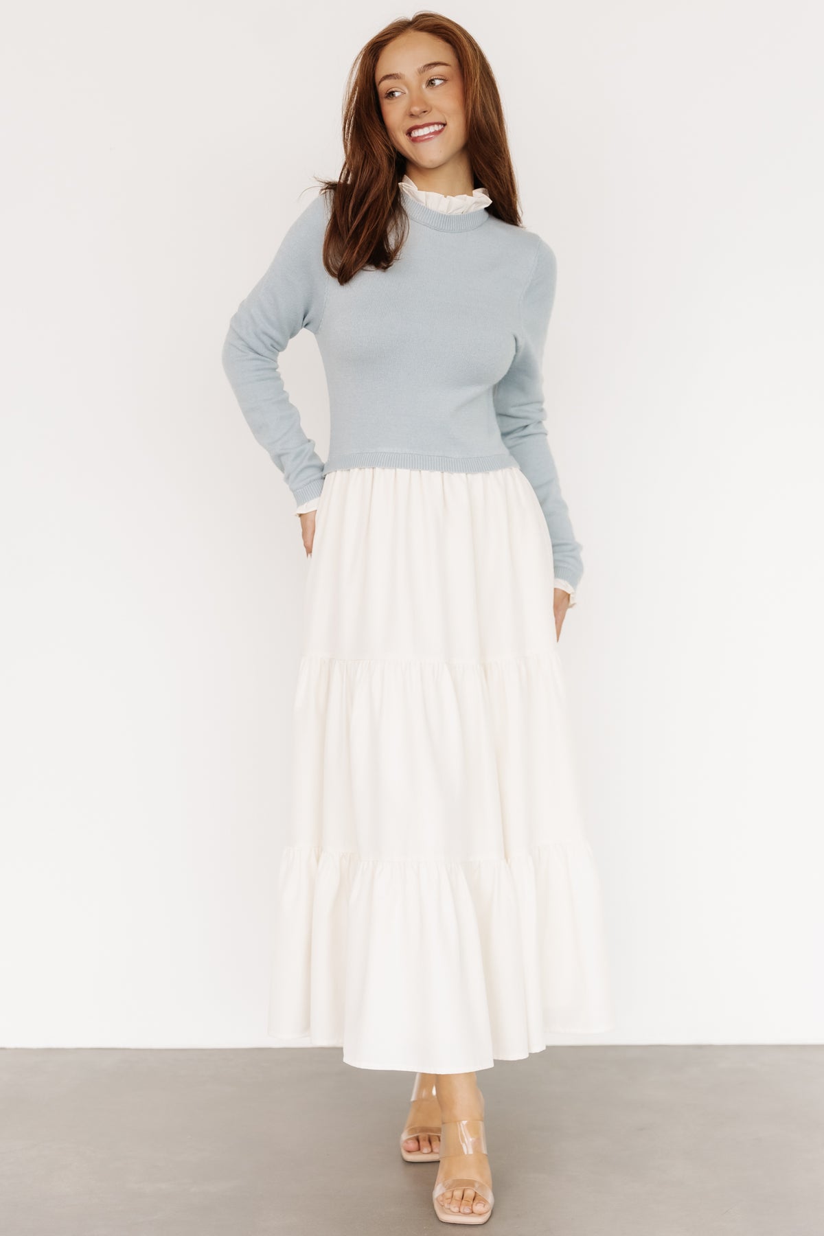 Front view of Sophie Sweater Dress in light blue and ivory showing ruffled neckline, long sleeves, and tiered maxi skirt with pockets, on model.